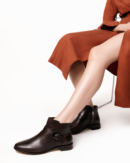 modelo usando Bota feminina em couro legitimo com cano curto cor marrom café. salto baixo